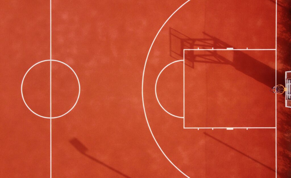 Overhead view of 3/4 of a red outdoor basketball court